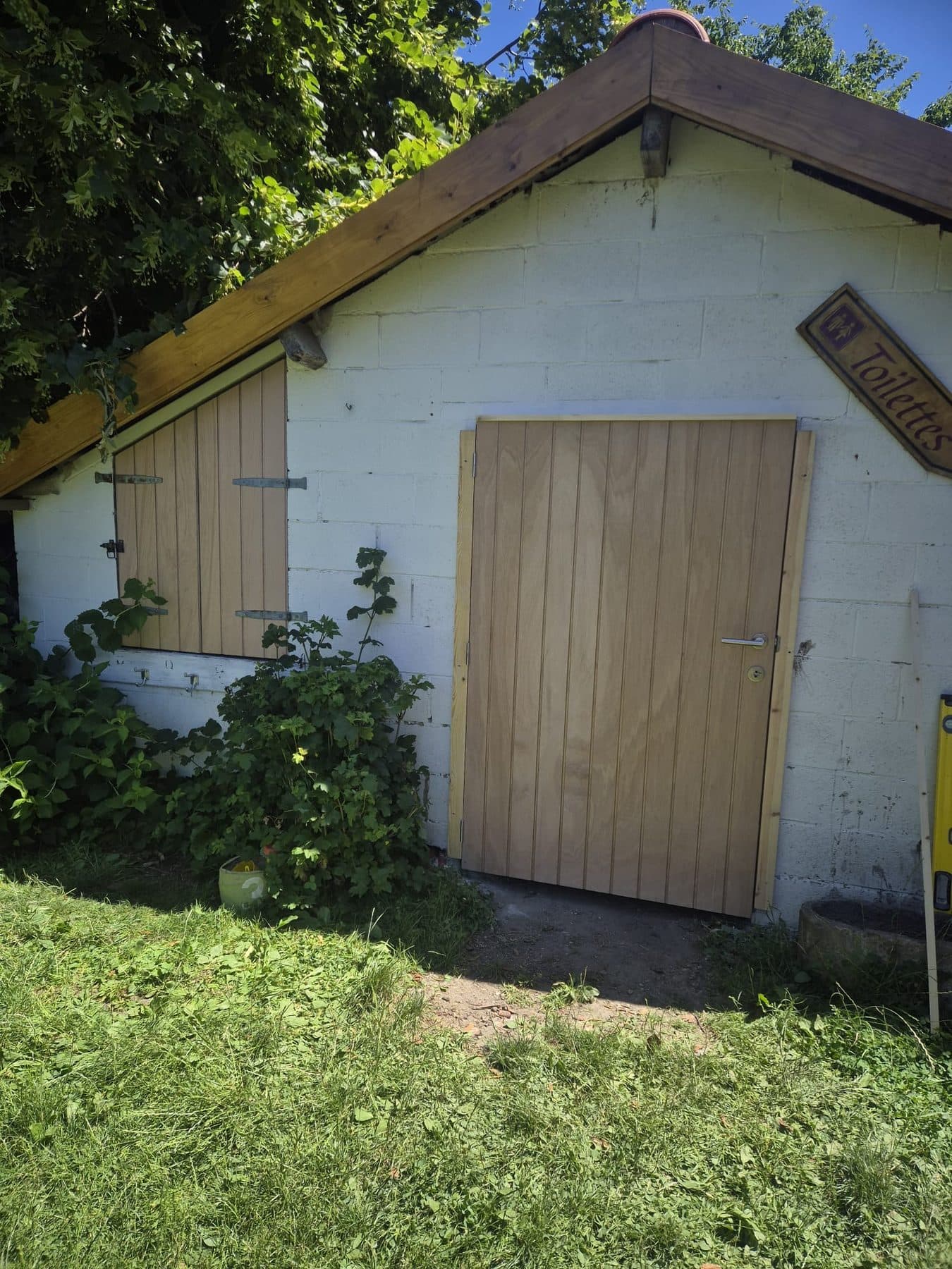 Porte en bois neuve posée sur un abri de jardin en briques
