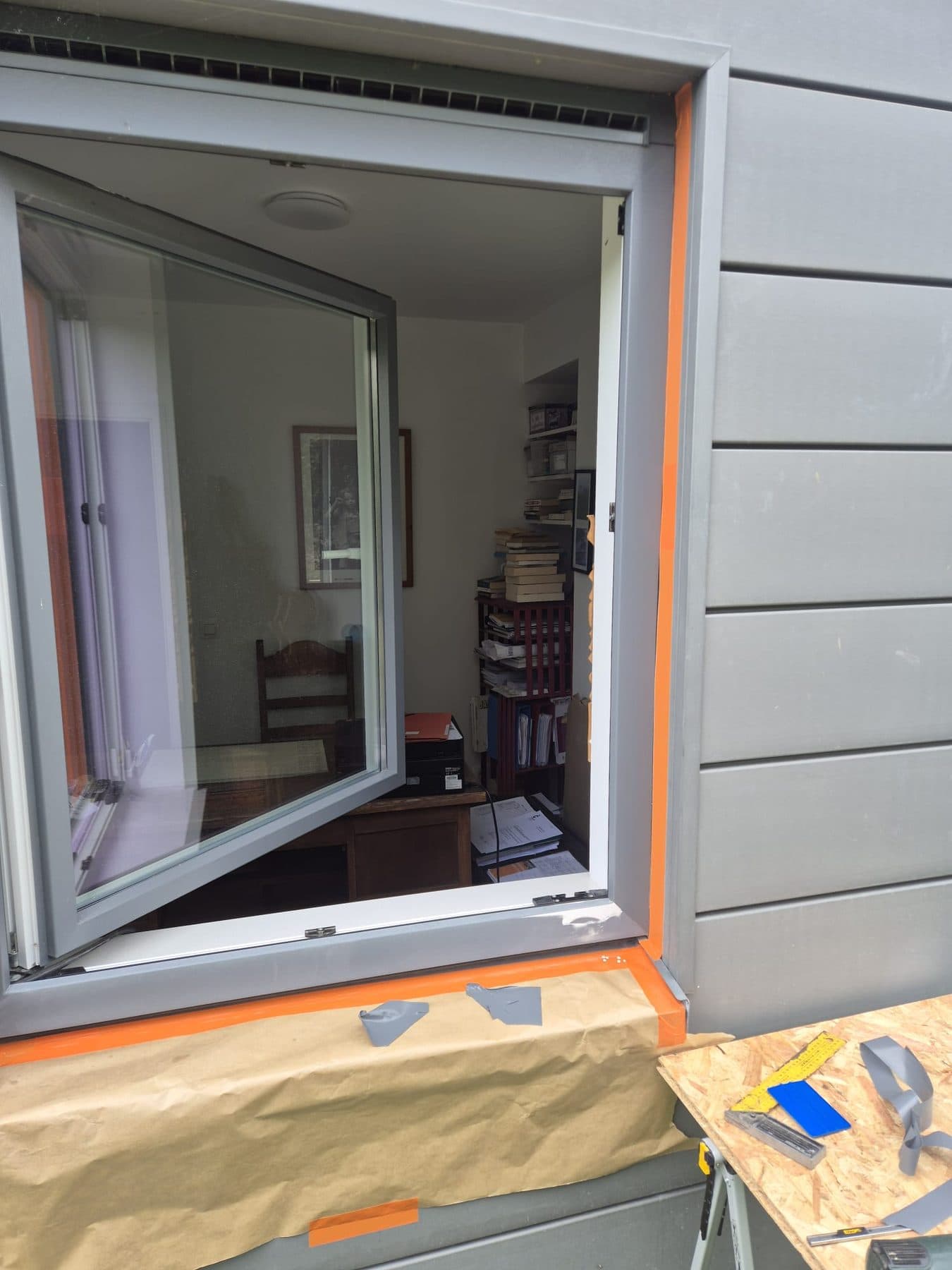 Châssis en cours de pose dans une façade en siding