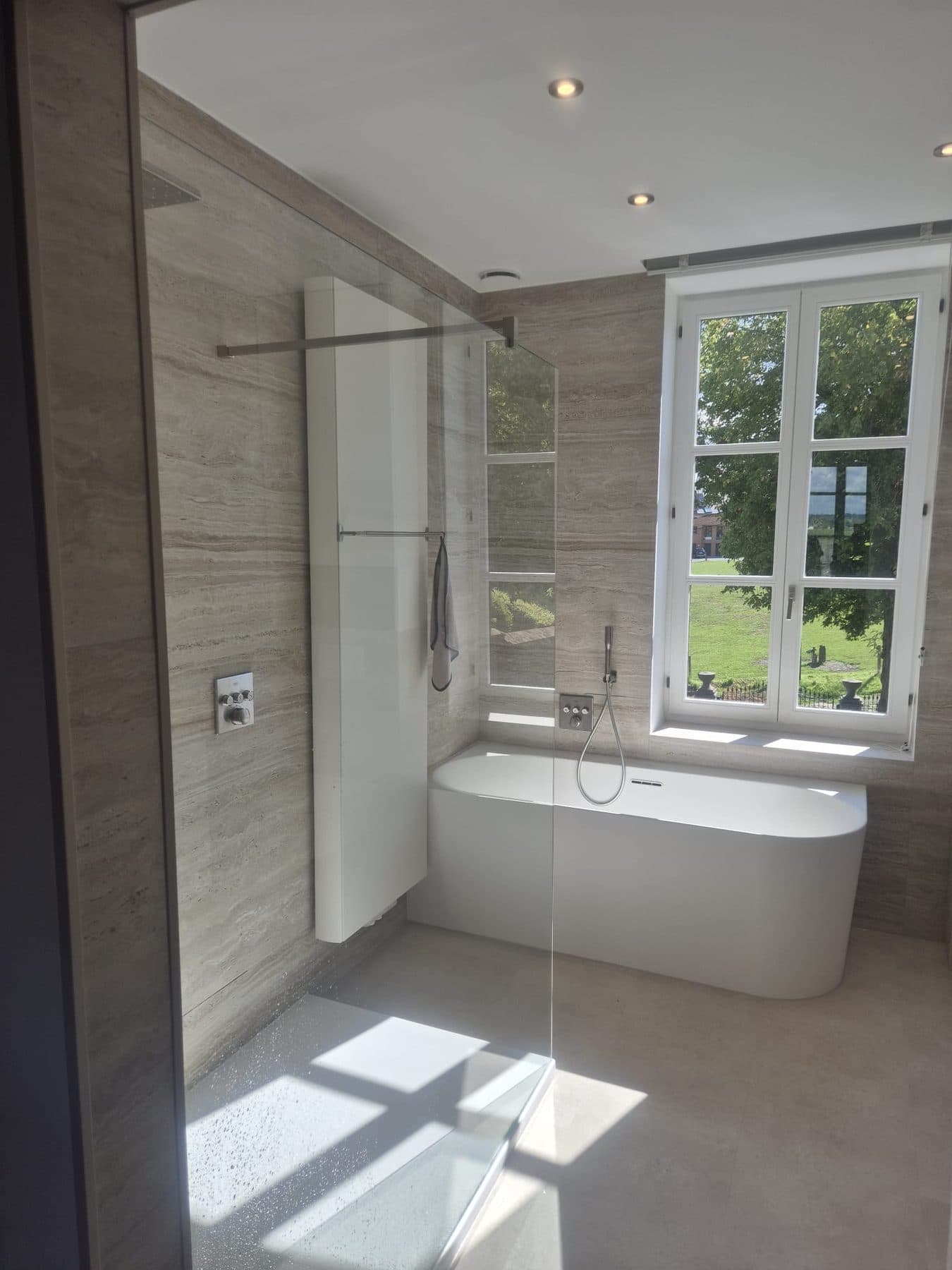 Salle de bain en travertin avec baignoire îlot et douche à l'italienne