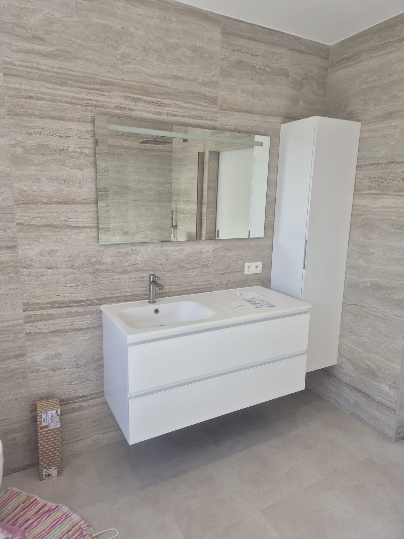 Meuble vasque suspendu et miroir dans une salle de bain en travertin
